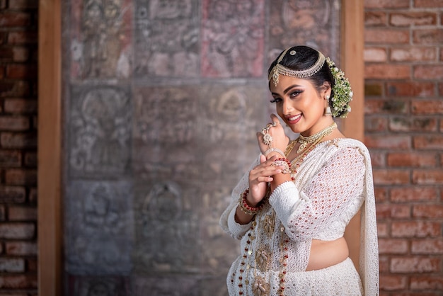 Una mujer con un sari blanco sonríe a la cámara.