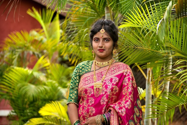 una mujer con un sari de pie frente a una palmera