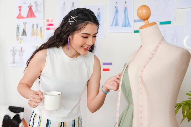 Mujer sastre asiática trabajando en ropa en taller de sastrería