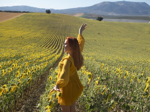 Mujer satisfecha de pie en el campo con girasoles