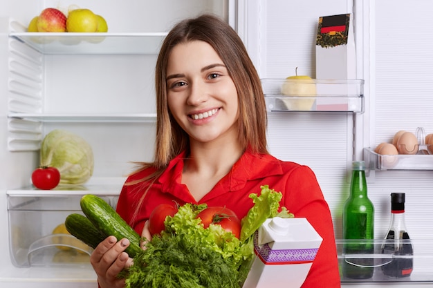 Mujer satisfecha tiene leche y verduras frescas