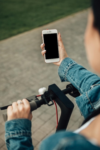 Mujer con scooter eléctrico de pie en las calles de la ciudad