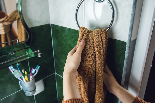 Mujer seca las manos con una toalla en el baño.