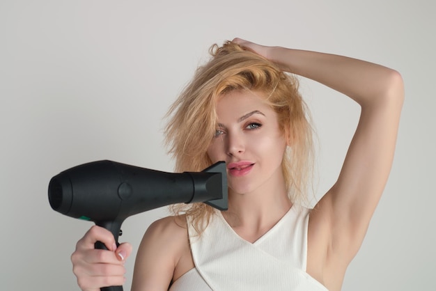 Mujer con secador de pelo aislado sobre fondo de estudio chica mantenga secador de pelo mujer joven secando pelos con