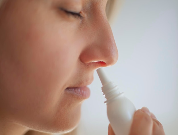 Una mujer con secreción nasal sostiene un medicamento en la mano.