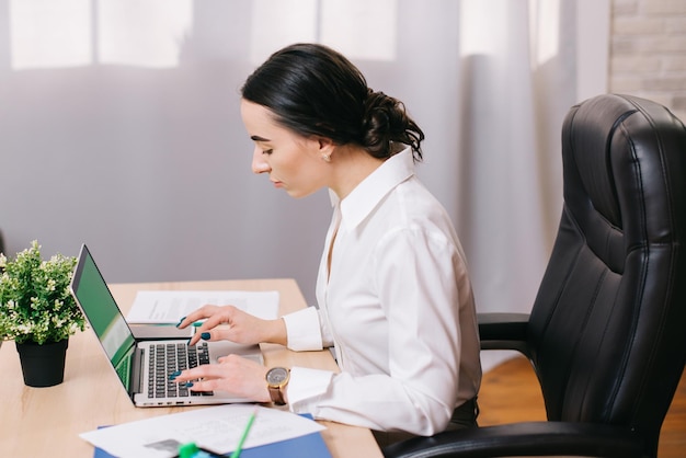 Mujer secretaria escribiendo texto en una laptop en la oficina