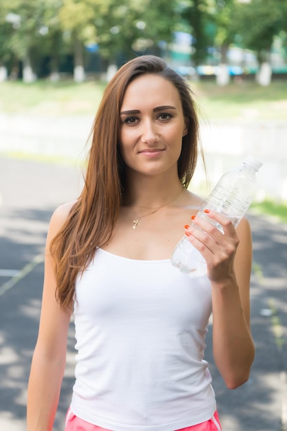 Mujer sedienta tiene botella de agua. Concepto de equilibrio de sed y agua. Señales de que definitivamente necesitas prestar atención a la hidratación de tu cuerpo. Deporte y salud. La niña se preocupa por la hidratación del cuerpo durante el entrenamiento.