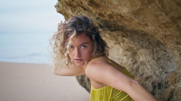 Mujer seductora bailando en la costa bajo una roca pedregosa cerca de la bailarina que se mueve