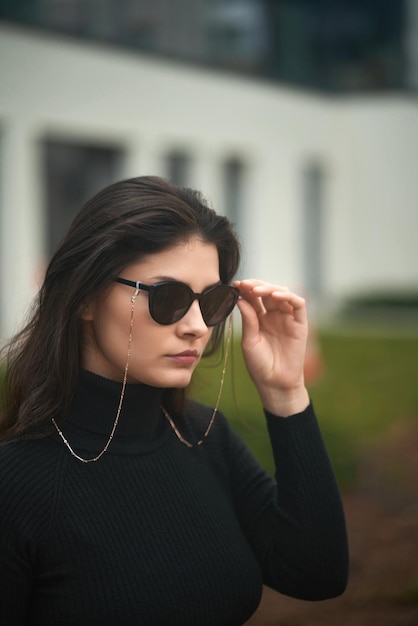 Una mujer segura y hermosa usa gafas de sol caras Concepto de accesorios de lujo para mujer Chica morena con estilo en la ciudad