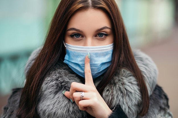 Mujer segura de pie fuera de la calle use una máscara desechable de cara azul para protegerse contra el virus