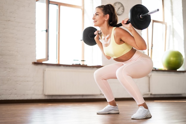 Una mujer segura de sí misma entrenando cardio deportivo en un gimnasio utiliza equipo deportivo y activo