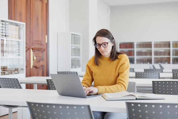 Mujer segura trabaja en la biblioteca en coworking en la computadora portátil o en la oficina estudiante está estudiando en línea
