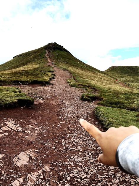 Foto mujer señalando el camino de la montaña contra el cielo