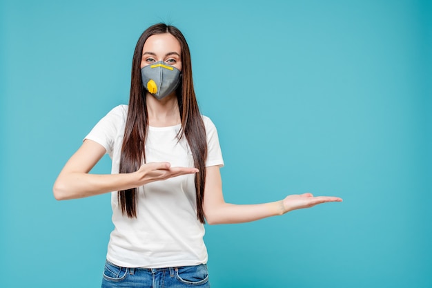 Foto mujer señalando con el dedo a copyspace en mano con máscara de respirador