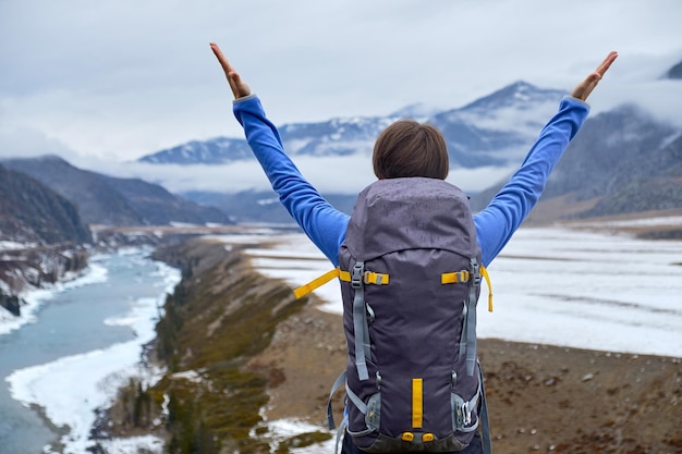 Foto mujer de senderismo con una mochila al atardecer levantó las manos hermosa joven viaja por las montañas