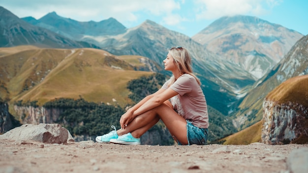 Mujer de senderismo en las montañas en el día soleado. Vista de Kazbegi, Georgia