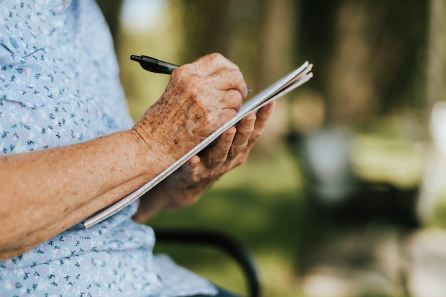 Mujer Senior anotando sus recuerdos en un cuaderno