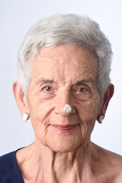 Mujer Senior aplicando crema o crema hidratante en la cara