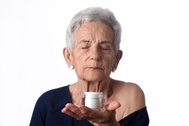 Mujer Senior aplicando crema o crema hidratante en la cara