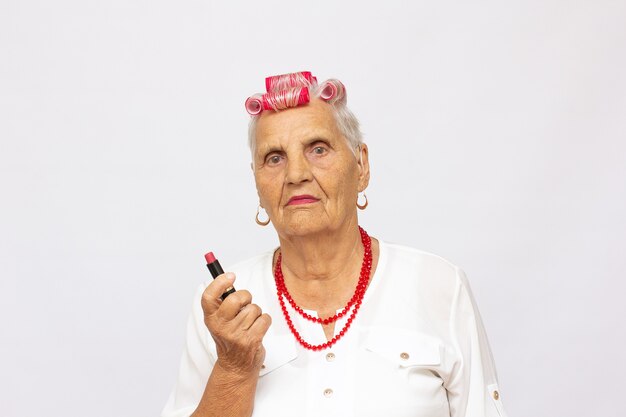 Mujer Senior aplicando lápiz labial rosa