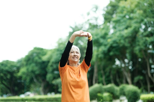 Mujer senior atlética estirando los brazos en el parque