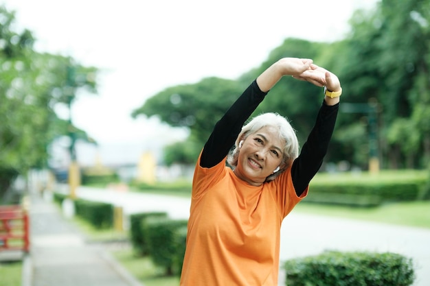 Mujer senior atlética estirando los brazos en el parque