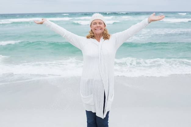 Mujer senior casual con los brazos extendidos en la playa