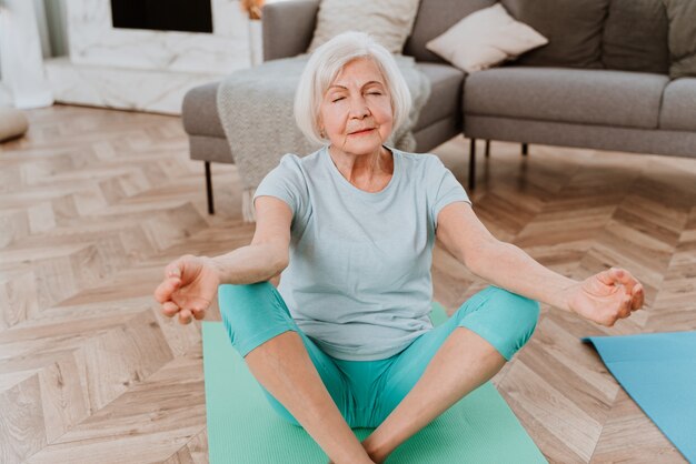 Mujer senior deportiva haciendo ejercicios de fitness y relajación en casa - Ancianos entrenando para mantenerse sanos y en forma