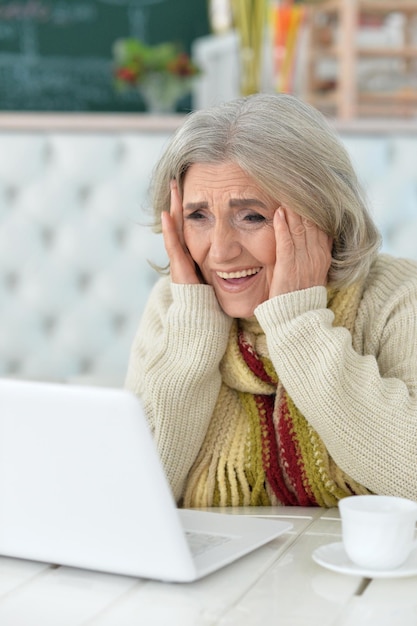 Mujer senior emocional con laptop