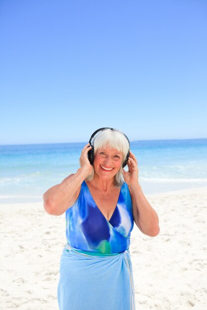 Mujer Senior escuchando música junto al mar