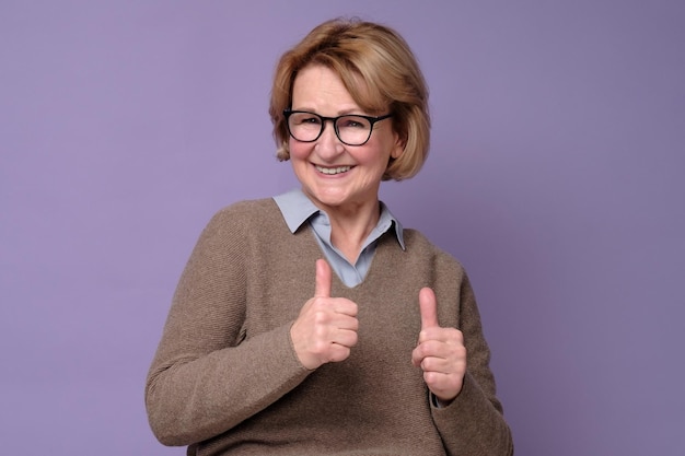 Mujer senior feliz caucásica mostrando sus dos pulgares para aprobar la elección