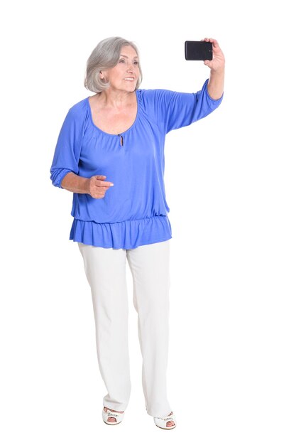 Mujer senior feliz de cuerpo entero tomando selfie aislado en blanco