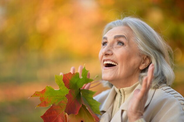 Mujer senior feliz posando al aire libre en otoño