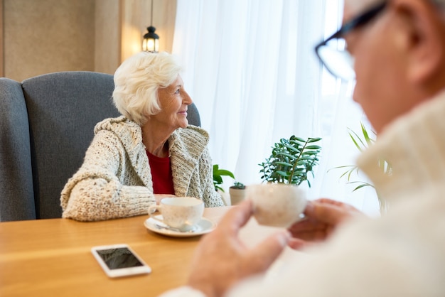 Mujer Senior pensativa en la mesa de café