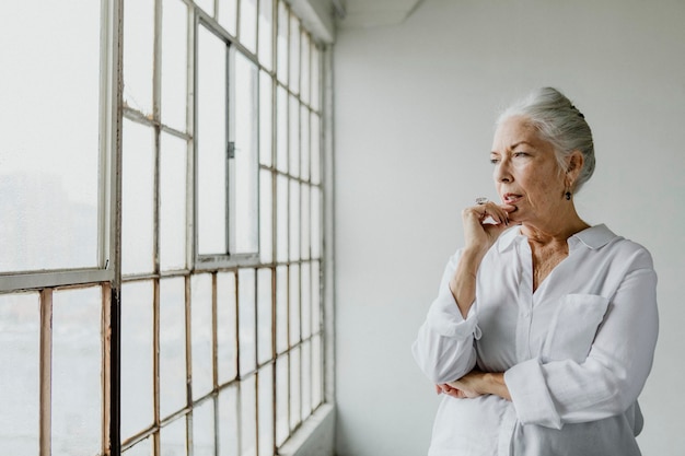 Mujer senior pensativa mirando por la ventana