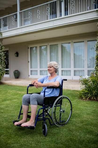 Mujer senior pensativa sentada en silla de ruedas