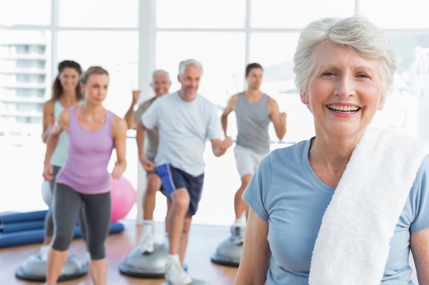 Mujer Senior con personas haciendo ejercicio en el gimnasio