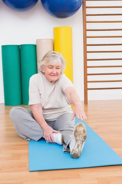 Mujer Senior que trabaja en la estera del ejercicio