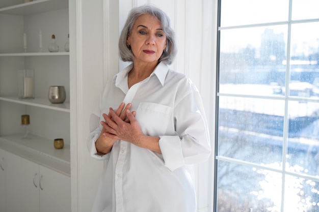 Foto mujer senior de tiro medio cerca de la ventana