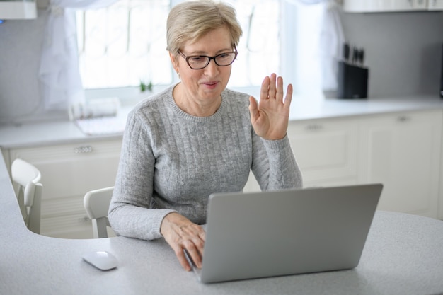 Una mujer senior trabaja en casa utilizando tecnología moderna en la vida cotidiana.