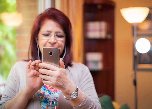 Mujer Senior usando nueva tecnología viendo videos en su teléfono inteligente