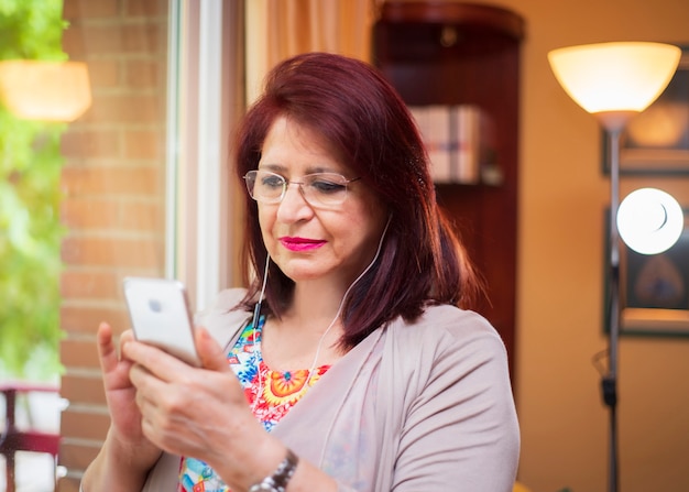 Mujer Senior usando nueva tecnología viendo videos en su teléfono inteligente