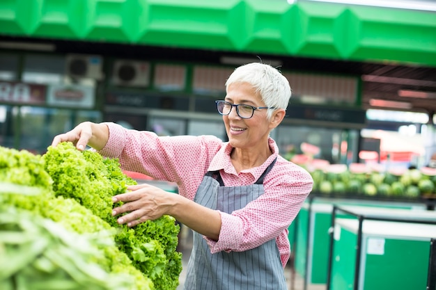 Mujer Senior vende lechuga en el mercado