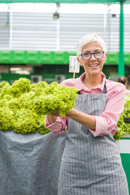 Mujer Senior vende lechuga en el mercado