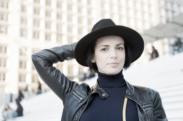 Mujer sensual con cabello morena, peinado. Mujer en pose de sombrero negro en las escaleras en parís, francia, moda. Belleza, mirada, maquillaje. Moda, accesorio, estilo. Cuidado de la piel, juventud, rostro.