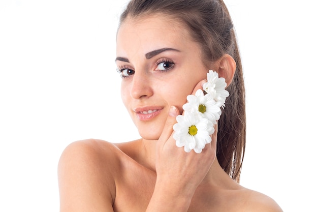 Mujer sensual cuida su piel con flores blancas en manos aisladas en estudio