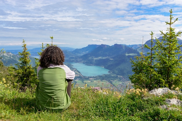 Mujer sentada en el acantilado y mirando el paisaje