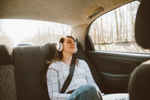 Mujer sentada en los asientos traseros del automóvil y escuchando música concepto de viaje en automóvil