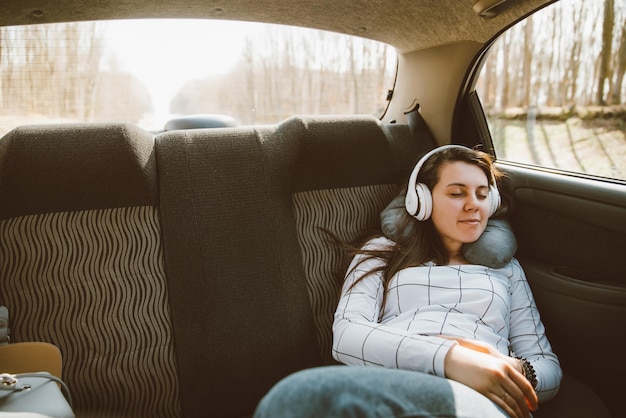 Mujer sentada en los asientos traseros de los autos y escuchando música en los viajes en auto c