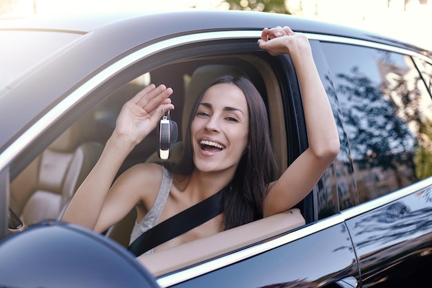 Mujer sentada en un auto nuevo y sosteniendo llaves